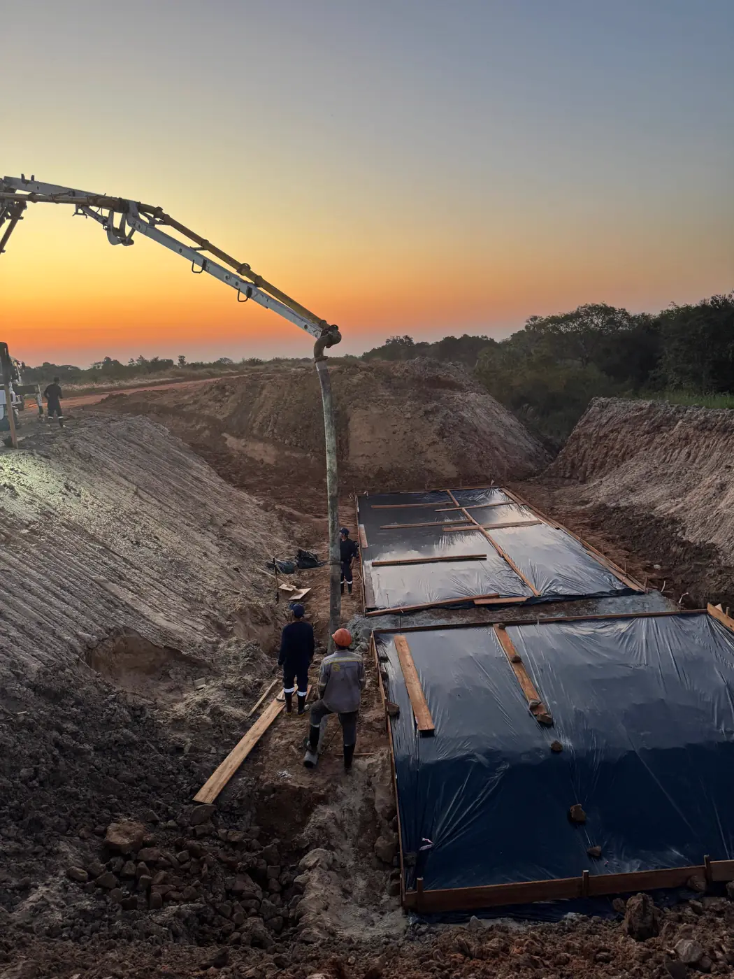 Bomba de hormigón trabajando sobre las losas de fundación al atardecer