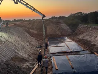 Bomba de hormigón trabajando sobre las losas de fundación al atardecer
